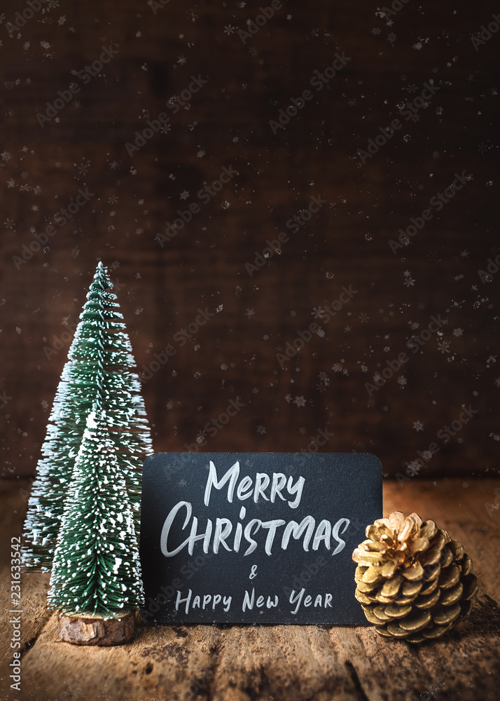Poster merry christmas and happy new year on blackboard with xmas tree and gold pine cone and snow falling 