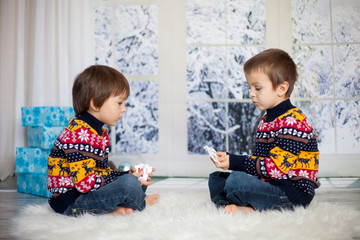 Two adorable children, boy brothers, playing cards at home, wintertime