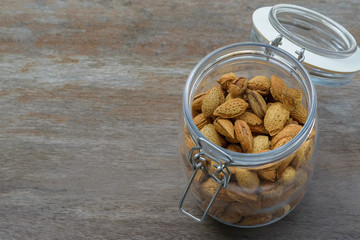 Almond seeds in the glass jar on the wooden table background