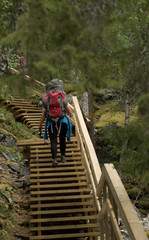 Strong girl climbing upstairs with backpack on hiking trail