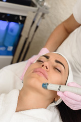 Young woman having ultrasound face peeling in spa salon