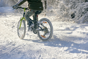 Fototapeta na wymiar Closeup of young boy with bicycle on snow cover road