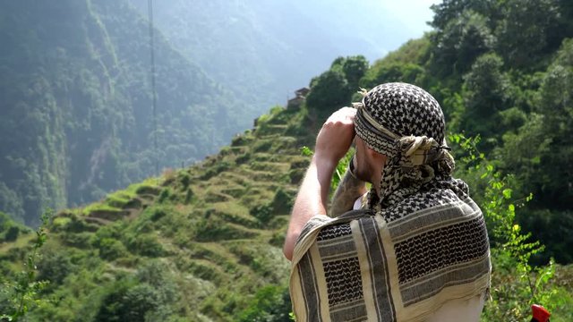 Hiker looking through binoculars on a trekking trail to the Annapurna base camp, the Himalayas, Nepal.