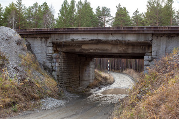Country road in autumn after the rain under the railway bridge
