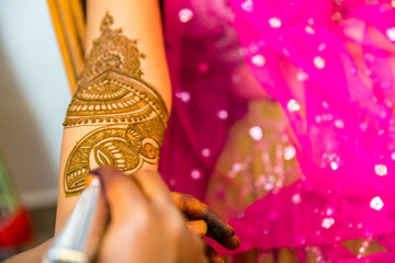 Artist applying henna tattoo on women hands. Mehndi is traditional Indian decorative art. Close-up