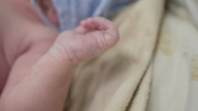 Tiny hand fingers of newborn baby lying in the maternity hospital bed