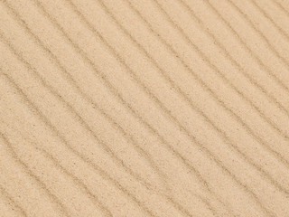 Diagonal waves of sand. Sandy texture background.