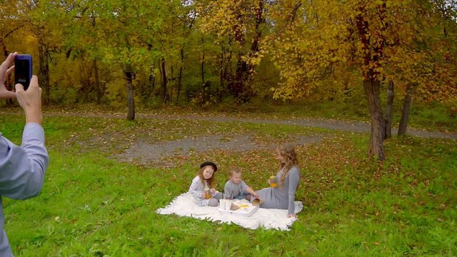 family autumn in the Park, picnic, dad takes pictures of his wife and children