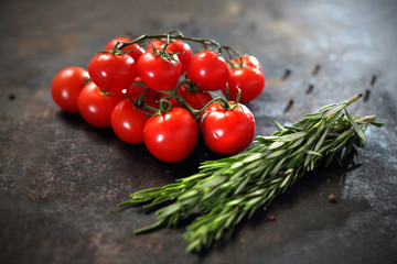 Pomidory i rozmaryn Gałązka pomidorów koktajlowych i aromatycznych ziół rozmarynu na czarnym tle. - obrazy, fototapety, plakaty