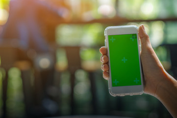 The view is cut out of the woman's hand holding a smart phone with a blank screen for text message space or text message content reading on a mobile phone. Green screen