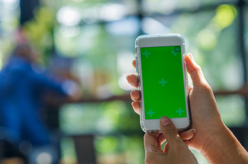 The view is cut out of the woman's hand holding a smart phone with a blank screen for text message space or text message content reading on a mobile phone. Green screen