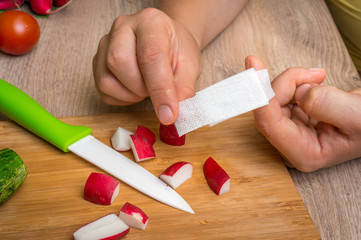 Woman is applying band aid plaster on her finger