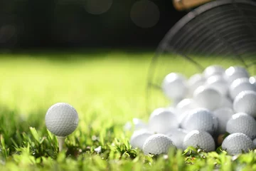 Foto auf Acrylglas Golfball auf Tee und Golfbälle im Korb auf grünem Gras zum Üben © amenic181