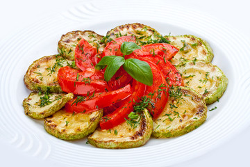 Fried zucchini with tomatoes on a white plate