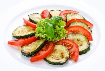 Fried vegetable marrows with greenery and tomatoes.