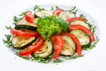 Fried vegetable marrows with greenery and tomatoes.