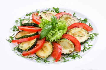 Fried vegetable marrows with greenery and tomatoes.