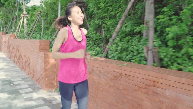 Healthy beautiful young Asian runner woman in sports clothing running and jogging on street in urban city park. Lifestyle fit and active women exercise in the city concept.