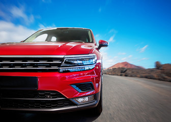 The image in front of the sports car scene behind as the sun going down with wind turbines in the back.