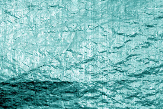 Crumpled transparent plastic  surface in cyan color.