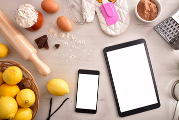 Pastry ingredients on white wooden table and mobile devices top