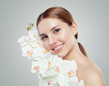 Young smiling woman with healthy skin and white orchid flowers - Powered by Adobe