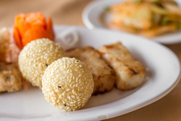The set of fried dimsum , Hongkong food with the various of fried flour menu with different shape such as round and panel with the orange carrot flower in the white dish on the table. 