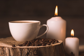 white cup of coffee, candles, and coffee beans 