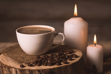 Fototapeta na wymiar white cup of coffee, candles, and coffee beans 