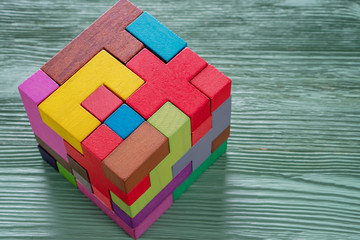 The cube is made up of multi-colored wooden shapes.