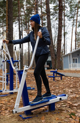 Naklejka premium A young women does exercises on a sports simulator in nature. Outdoor.