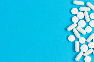 White prescription pills on blue background. 