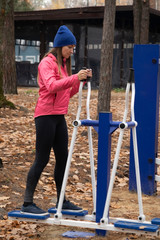 A young women does exercises on a sports simulator in nature. Outdoor.