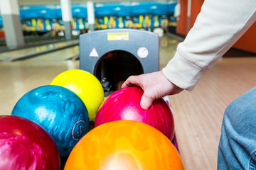 Close-up of a person's hand picking bowling ball from rack
