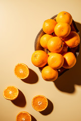 Flat lay with tangerines in metal bowl on beige backdrop