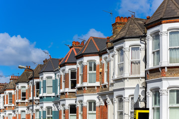 A row of typical British terraced houses in London with an estate agent sign