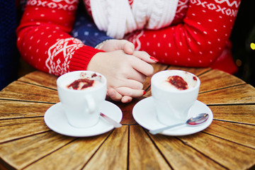 Couple drinking coffee in cafe and holding hands