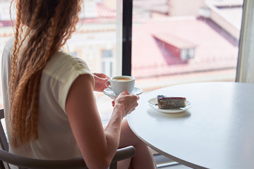 Curly redhead skinny woman sitting in cafe in front of window