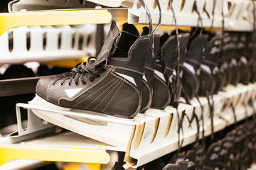 Rows of black ice skates, selective soft focus. Hire of winter sports equipment. Shelves with skates