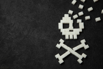 Skull from white sugar cubes on black background. Sugar kills and lot of fast ulevodov harmful to the body. Diabetes mellitus to death. Copy space for text