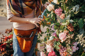 Female florist decorator in a sweater, color scarf and leather belt with pockets for an instructor...