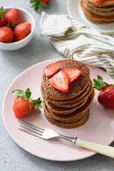 Chocolate pancakes with strawberries on pink plate, high angle view