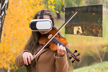 Young violinist playing in the park and sees virtual screen with fans at the concert
