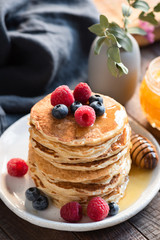 Oat Pancakes With Blueberries, Raspberries And Honey For Breakfast On White Plate On Wooden Table. Selective focus