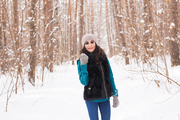 Young pretty woman walking in the winter snowy park at sunny day