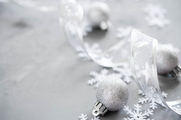 Silver Christmas background. Curly ribbon with decorative balls and snowflakes.