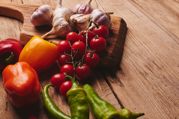 Fresh organic vegetables on wooden board close up. Cherry tomatoes, garlic, peppers and dill on a wooden table..