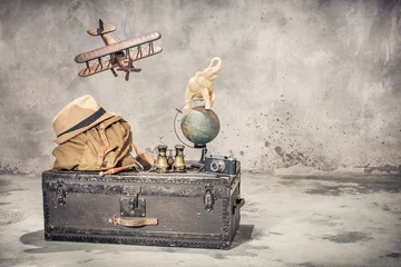 Wallpaper murals Old airplane Vintage old classic travel trunk luggage, flying wooden toy plane, elephant on aged globe, tourist backpack, hat, binoculars, film camera, magnifier. Travel by air concept. Retro style filtered photo