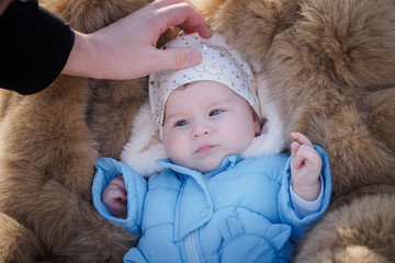 Fototapeta premium baby girl lying on fur bedspread looking at someone and smiling