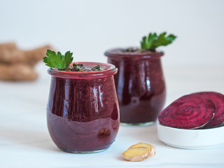 Fresh beetroot and ginger root smoothie. Beetroot smoothie in glass jar on white table. Shallow...